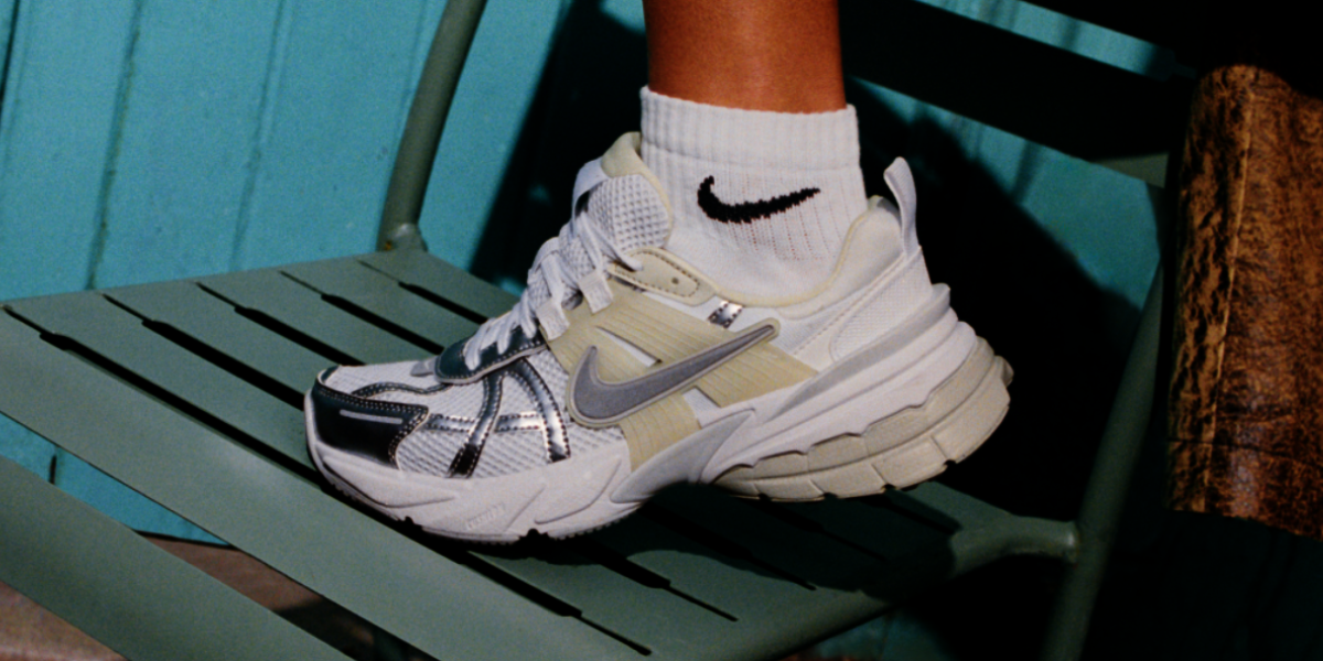 Weißer Nike Sneaker mit weißen Nike Socken Fuß auf einem Metallstuhl abgelegt