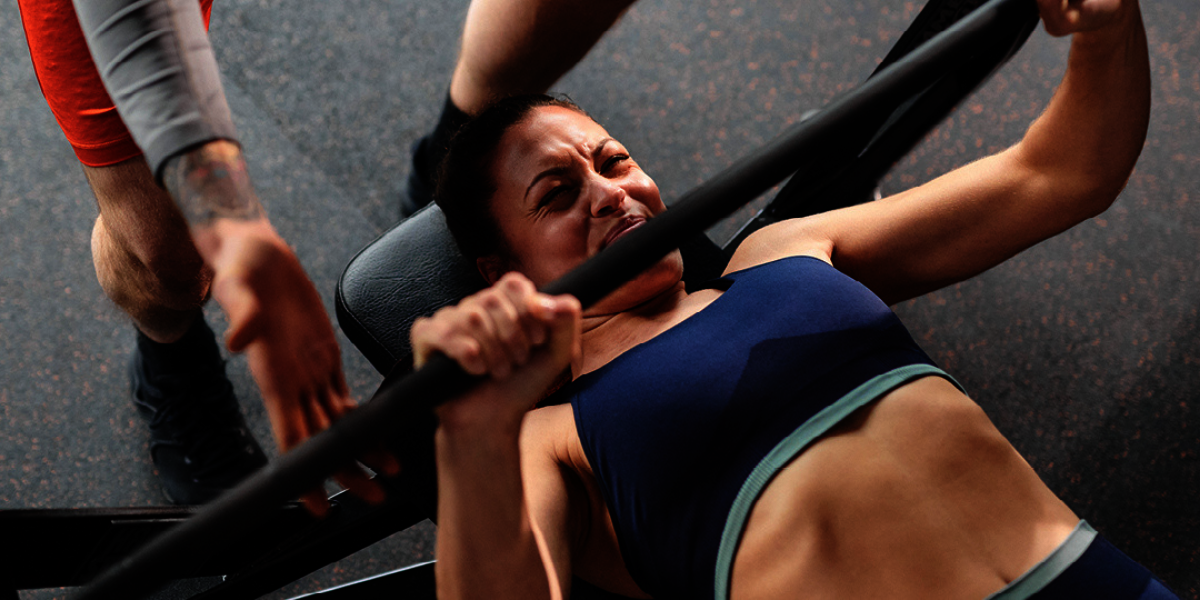 Frau liegend auf einer Hantelback und am Brustdrücken Krafttraining