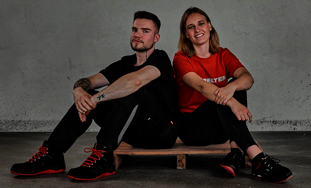 zwei Personen Frau und Mann auf dem Boden sitzten mit Elton sicherheit schuhen 