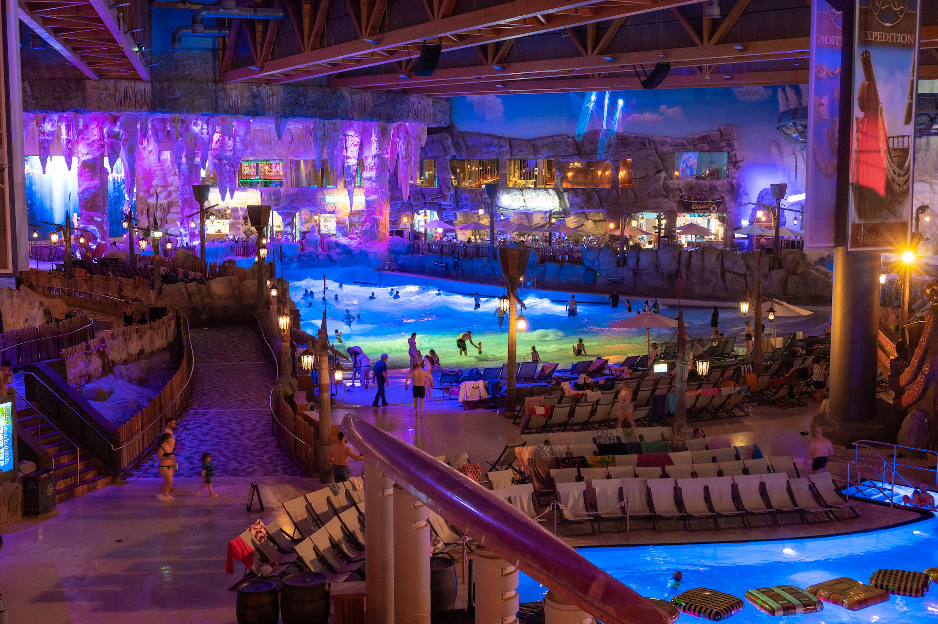 Schwimmbad Halle von innen mit ambiente Beleuchtung Rutschen und Liegestühlen 